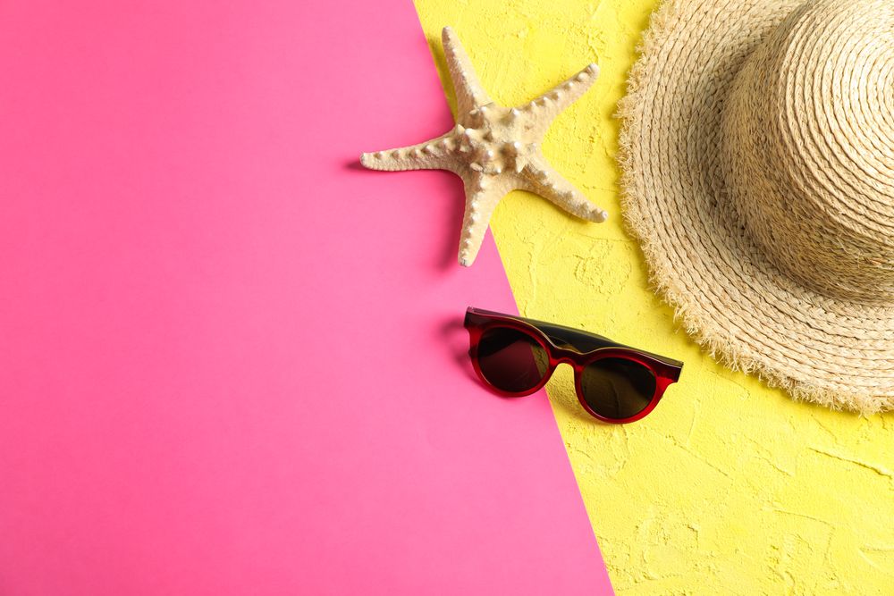 Composition with straw hat, sunglasses and starfish on two tone background, space for text