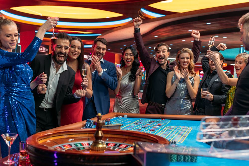 Cheerful Group of Rich Young People Gathered Around a Roulette Table at a Modern Casino.