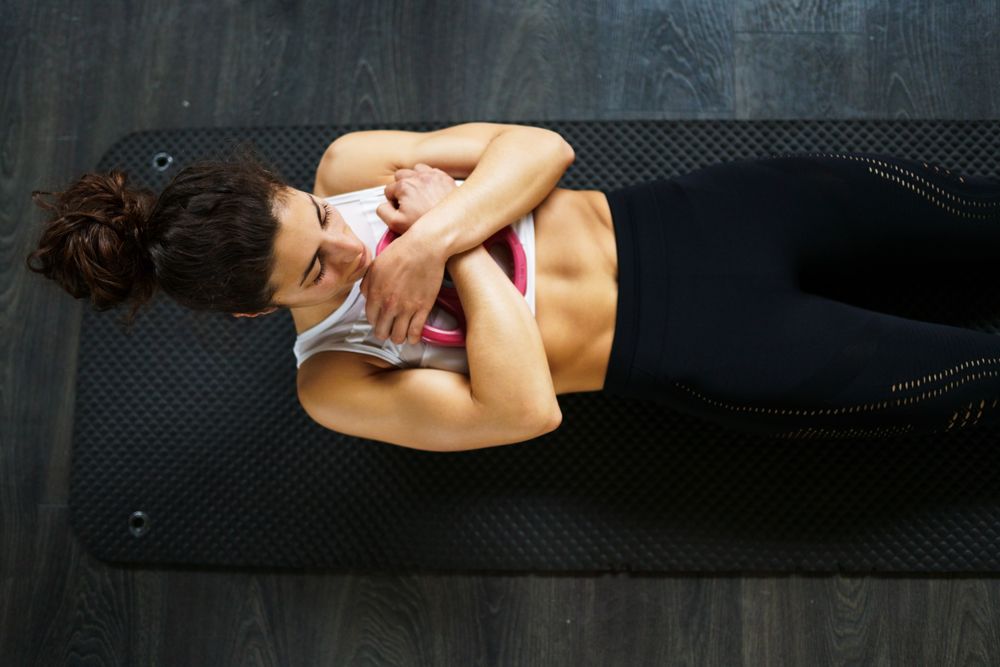 Fit woman doing sit ups with arms crossed over chest