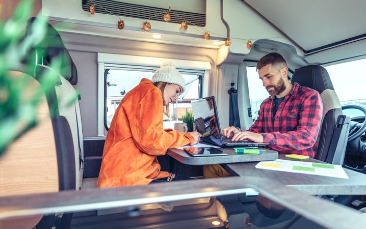 Male and female campers working remotely in back of van