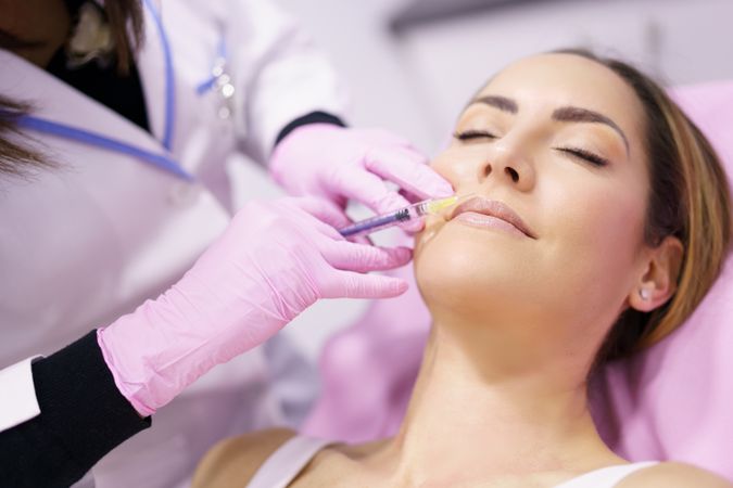 Woman having fillers injected into her lips