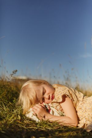 Calm little girl lying in countryside field