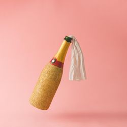 Molotov cocktail gold champagne bottle on pink background