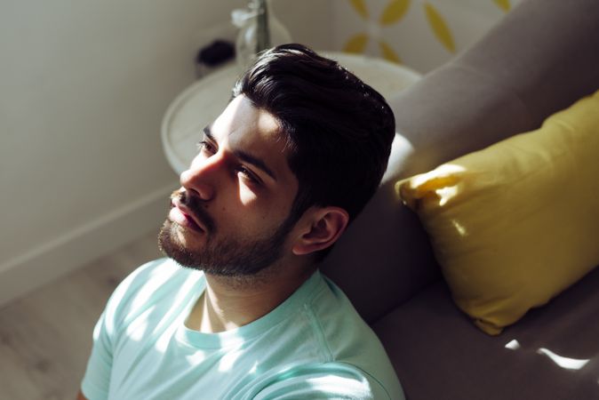 Young sad man sitting on couch at home