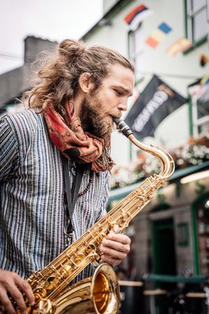 Male saxophonist plays sax in the street