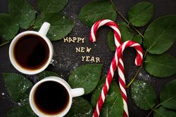 inscription of new year on a board with sprigs leaves and red candy