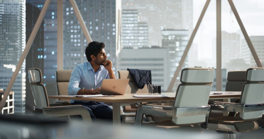 Portrait of a Young Indian Account Manager Working on a Laptop Computer in a Modern Corporate Office.