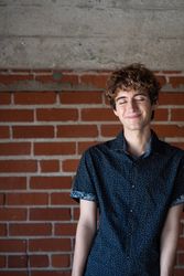 Portrait of nonbinary person with their eyes closed and smiling