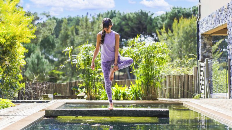 woman practicing yoga on a pool.
