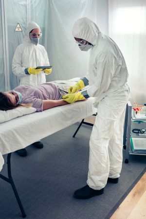 Doctors taking blood sample from patient lying on a gurney