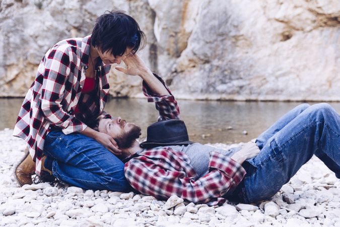 Positive woman and man resting on stone shore near river