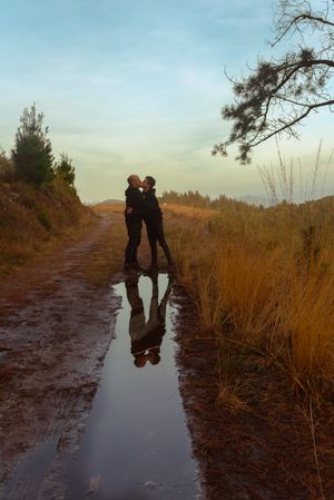 Men hugging and kissing near water puddle