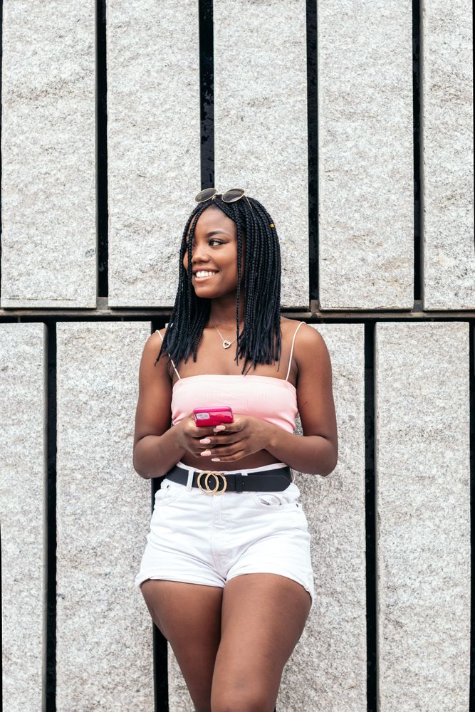 Portrait of a Black young woman enjoying in the city using smartphone