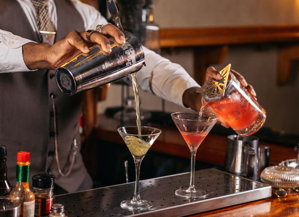Black bartender preparing a cocktail in a traditional cocktail bar
