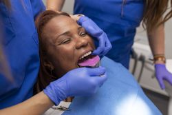 Close up of a dentist's hands placing an impression tray in patient's mouth