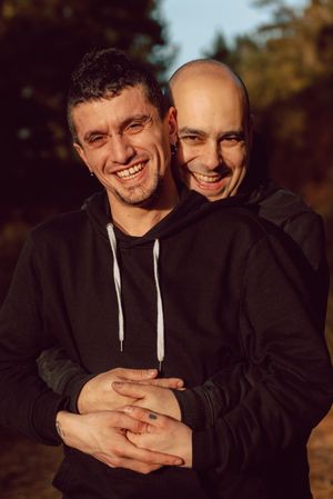 Smiling men hugging on path in park