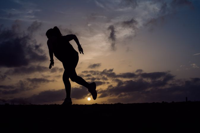 Jumping woman and sky with clouds at sunset