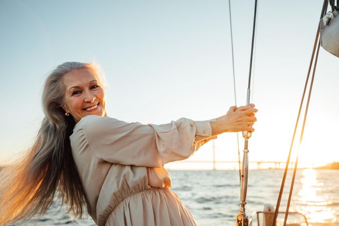Older woman smiling and holding the lines of a sailboat