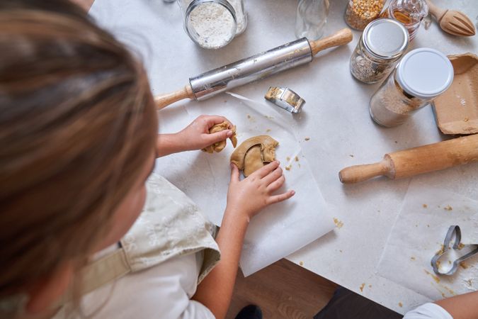 Crop child cutting out cookies from dough