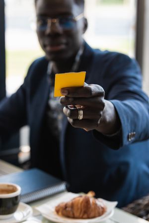 Crop Black executive with business card in cafe