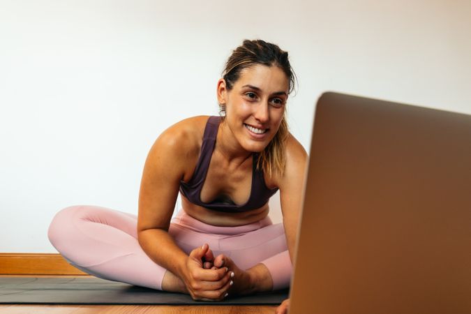 Woman in sportswear doing yoga with laptop at home