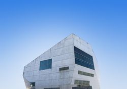 Grey modern building with unsymmetrical windows with blue sky