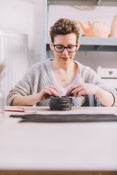 Adult woman putting clay roll on unfinished pot