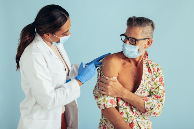 Female doctor giving coronavirus vaccine to mature man