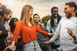 Friends laughing and dancing outdoors - warm tones