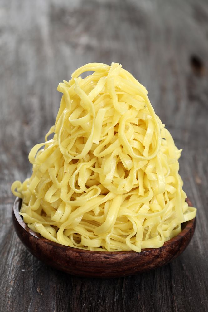 Close Up A Pile of Yellow Flat Noodle on Wooden Bowl
