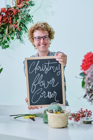 Mature woman demonstrating chalkboard with inscription in floral