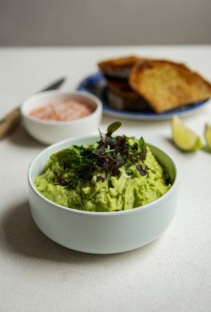 Guacamole in a light green bowl with toast