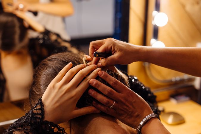 Female actress making hairstyle by illuminated mirror