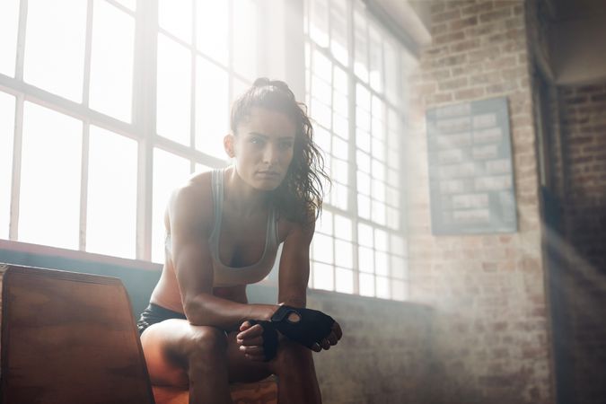 Portrait of confident fitness trainer sitting on at gym