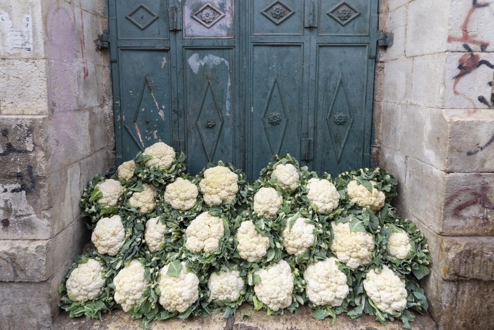 Bunch of stacked cauliflower in front of green door