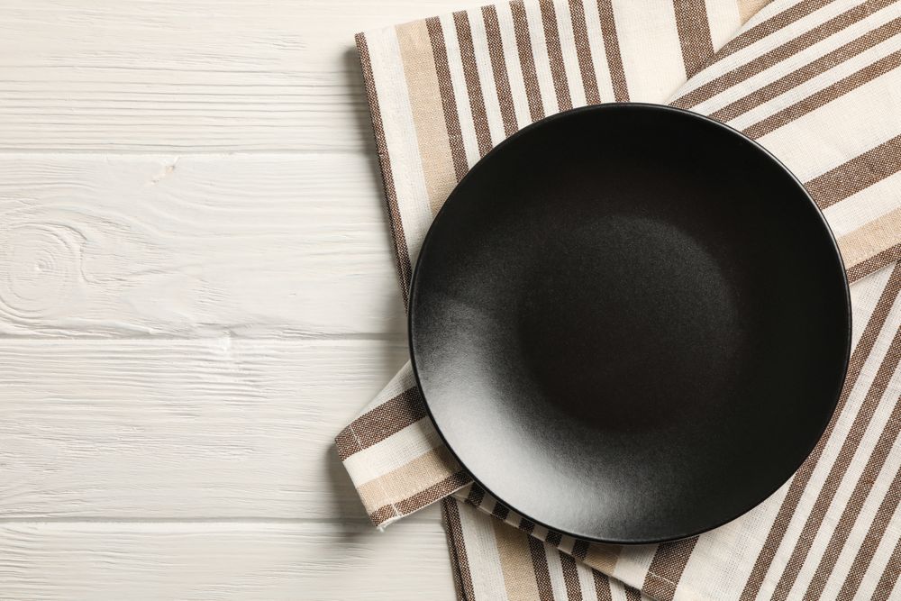 Kitchen towel with plate on wooden background, top view