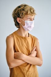 Contemplative boy in sterile mask on light background