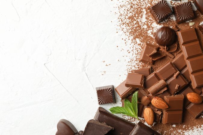 Chocolate, melted chocolate, coffee and almond on plain background
