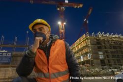 Engineer with facemask beside a building under construction worker at night 489nZb