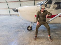 Pilot waiting beside retro plane in hangar