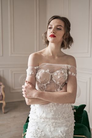 Magnificent pensive young bride in white lace dress looking away and pondering