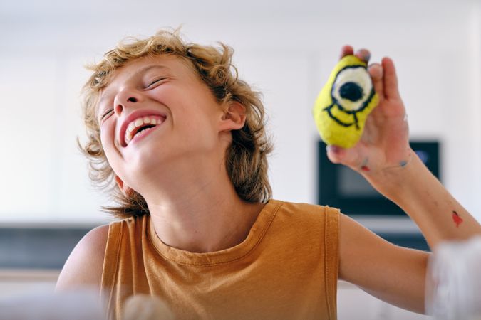 Excited boy with painted rock at home