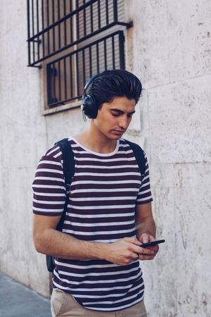 Young man with headphones and smartphone walking outdoors