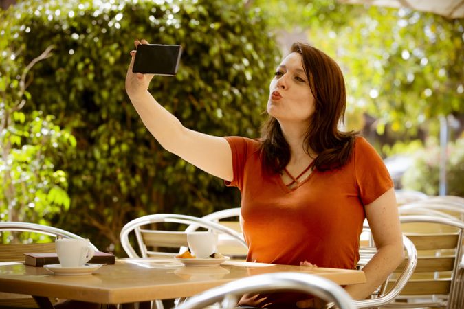 Woman talking selfie with smartphone in cafe