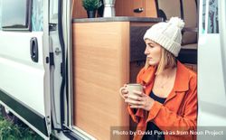 Female relaxing with coffee sitting on camper van step, close up 48Yv7b
