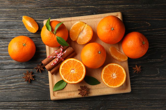 Board with mandarins and cinnamon on wooden background