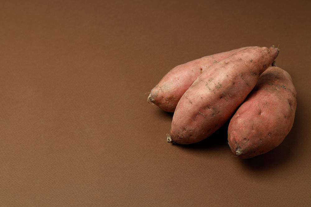Fresh sweet potato on a brown background