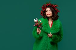 Woman in green coat and red berry wreath