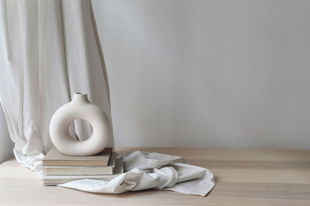 Modern organic shaped vase with old books on folded drapery