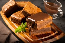 Wooden board of brownies with chocolate syrup and mint garnish